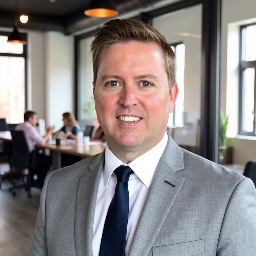 Patrick Gibson in a gray suit and navy tie